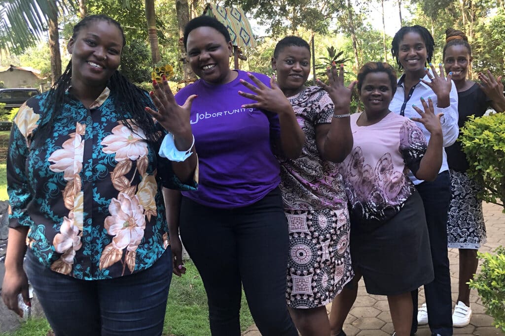 5 Tanzanian women stand and smile at the camera