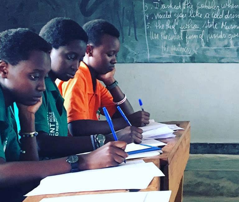 Three Rwandan students concentrate in the classroom