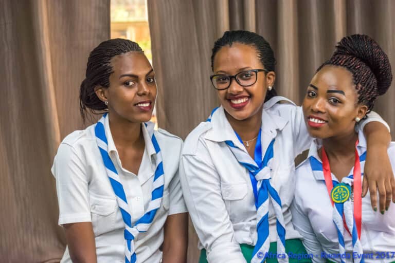 Three young women in matching uniforms smile at the camera