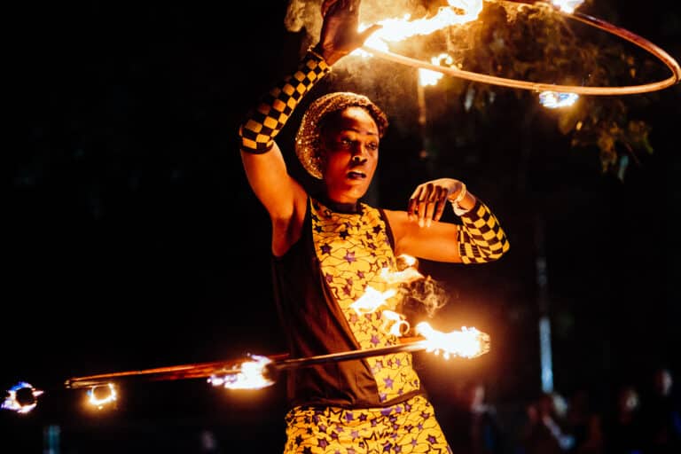 Un artiste de cirque fait tournoyer des cerceaux enflammés