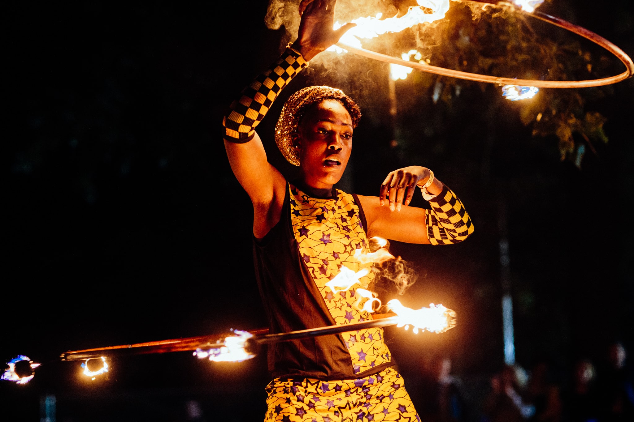 A circus performer twirls flaming hoops