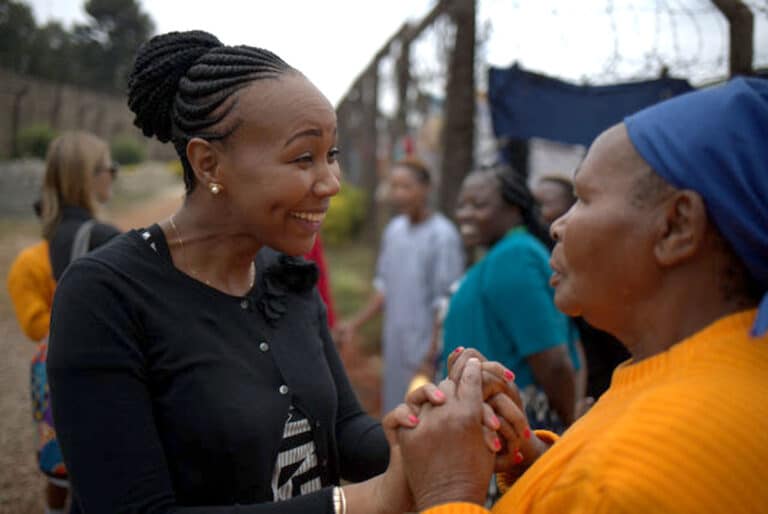 Une femme kenyane tient avec enthousiasme les mains d'une femme plus âgée.