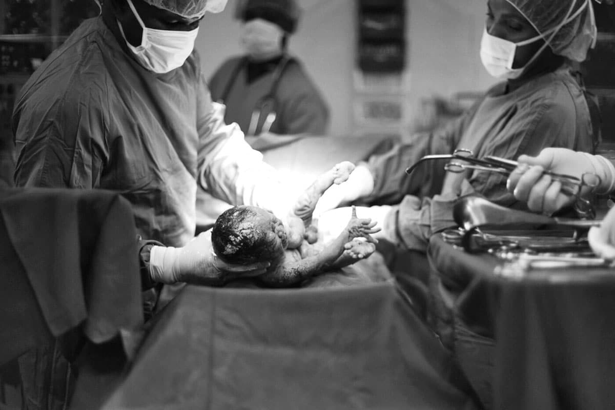 A black and white photo of a newborn in a doctor's hands