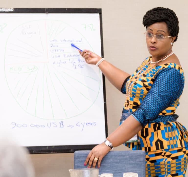 A Burundian woman stands at a whiteboard