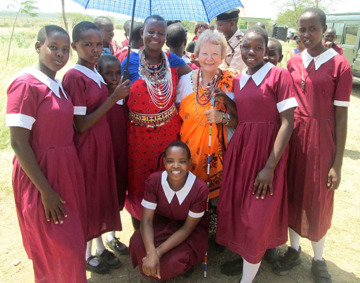 Schoolgirls in uniform surround an elderly white woman