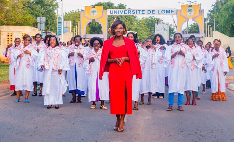 A large group of women in Togo stand behind a woman in a red dress