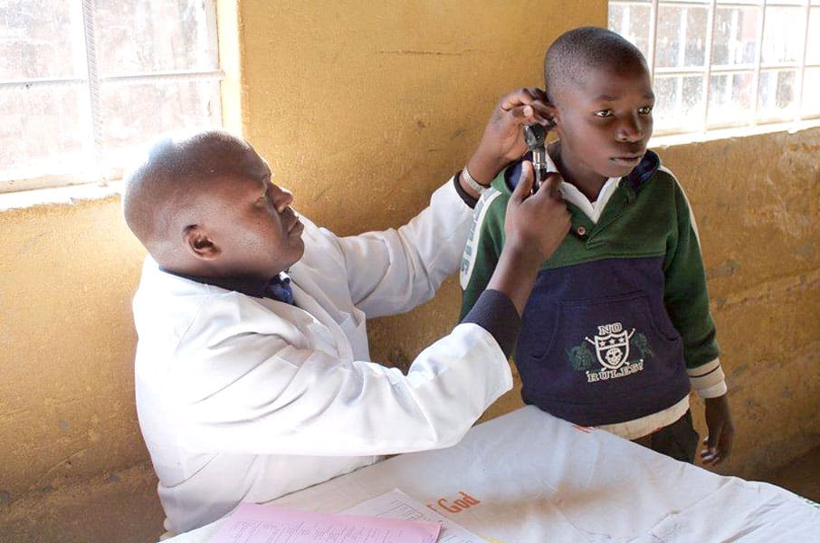A health professional checks the ears of an African student