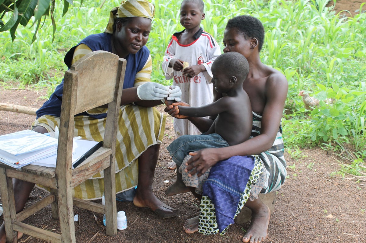 A community health worker gives a vaccine to a child in Togo