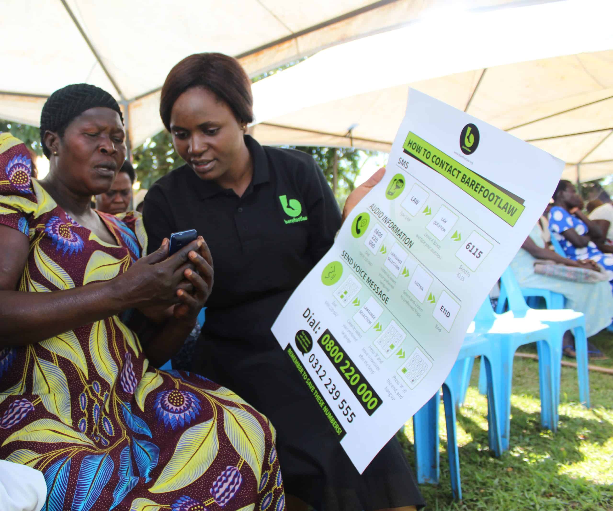 A woman instructs another woman with a poster and a phone