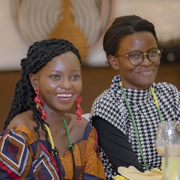 Two seated Black women smile beyond the camera