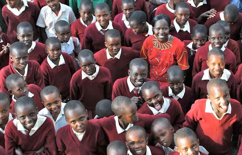 Kenyan girls in uniform look up at the camera and smile
