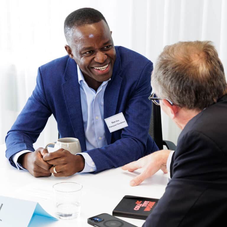 A smiling African man speaks with a white man
