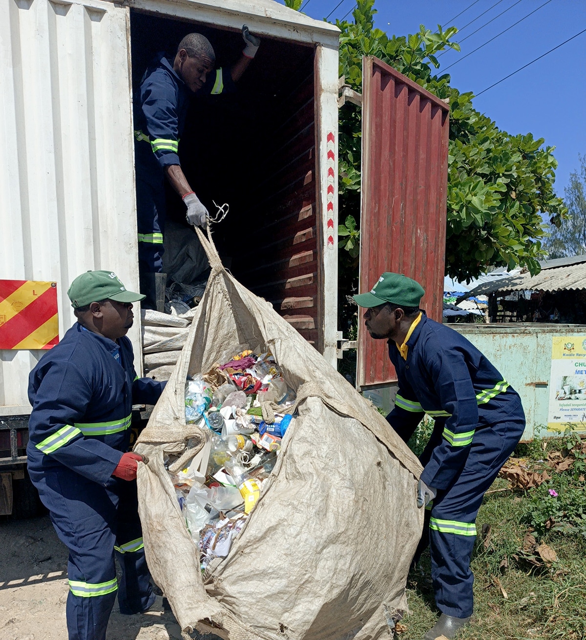 African men load a large bag of recycling into a truck