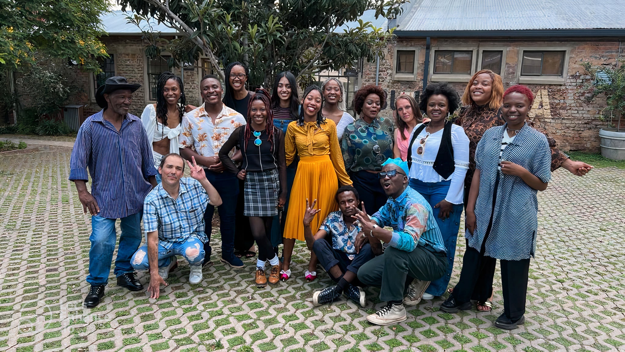 Over 10 people stand in a courtyard and smile