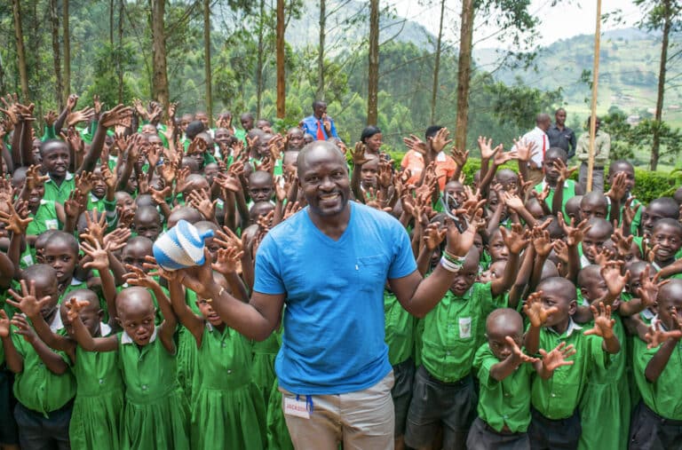 Twesigye Jackson Kaguri stands in front of a large group of students in uniform