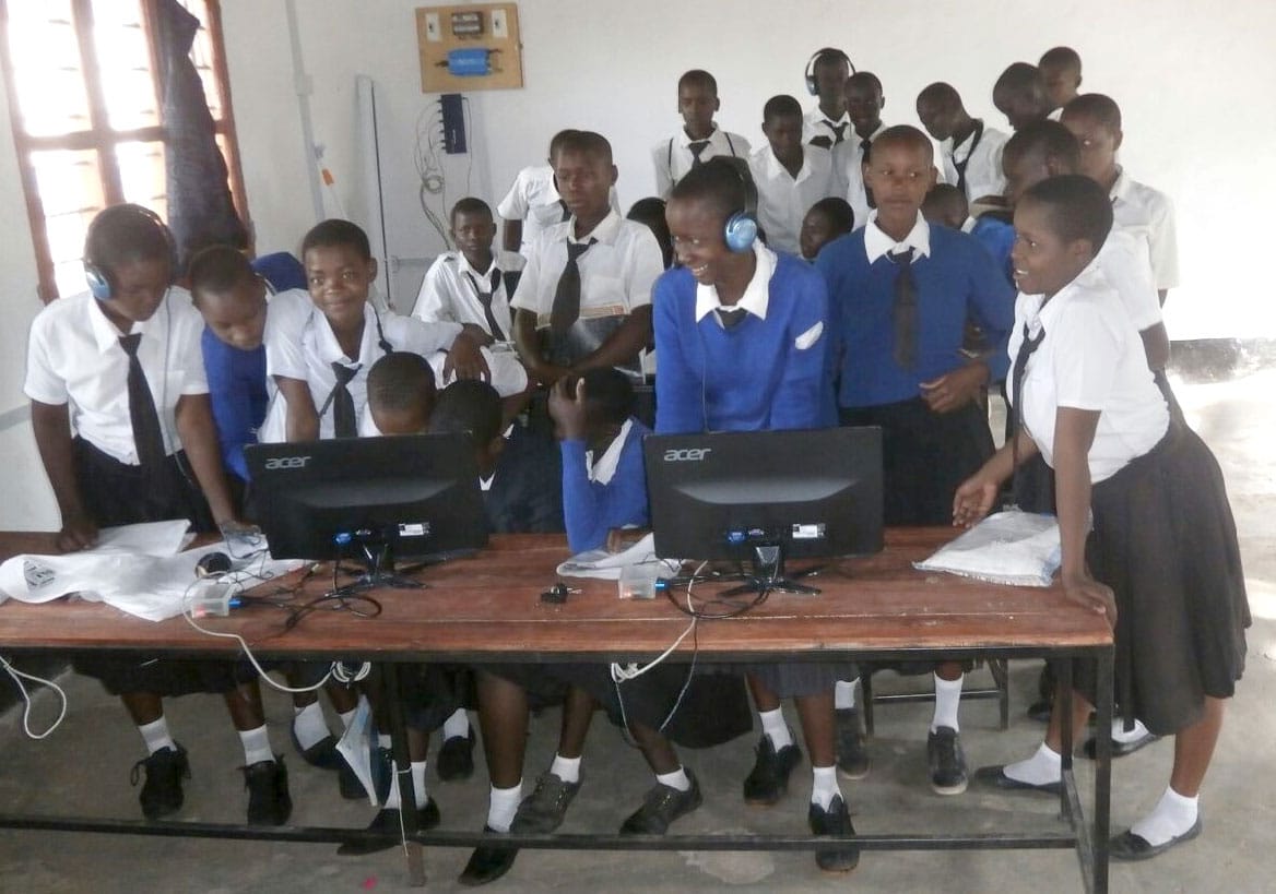 Des écoliers tanzaniens se rassemblent autour de deux ordinateurs