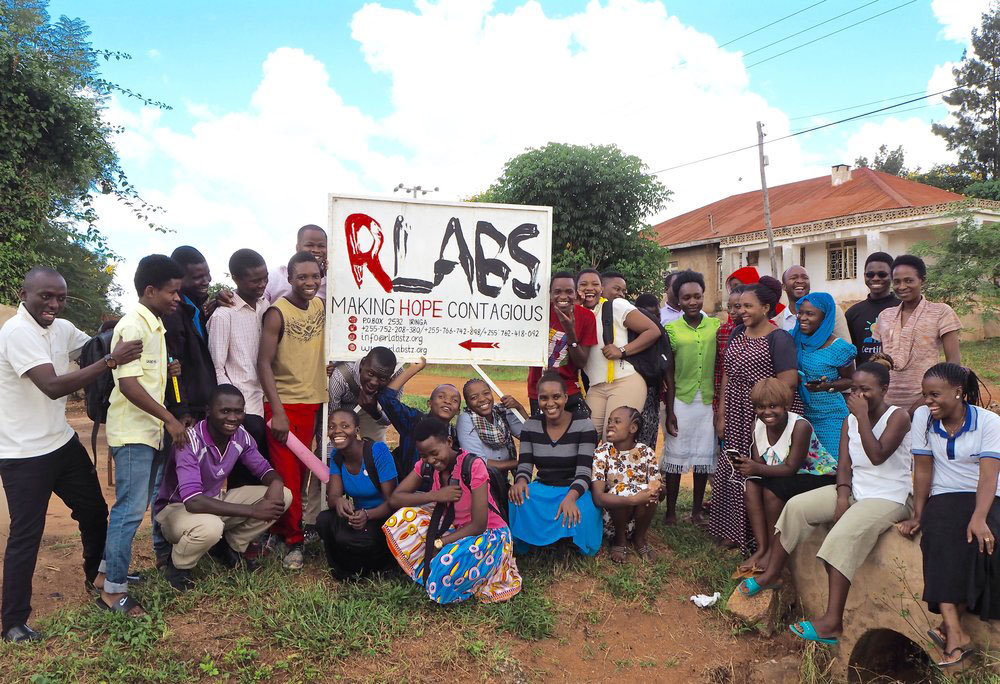 Jamii inakusanyika, ikicheka, karibu na ishara ya RLabs