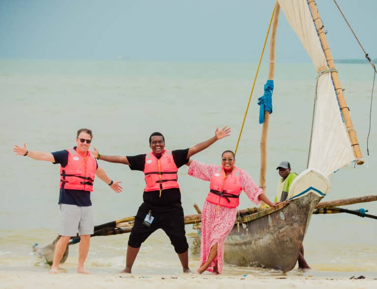Four adults pose by a dhow boat