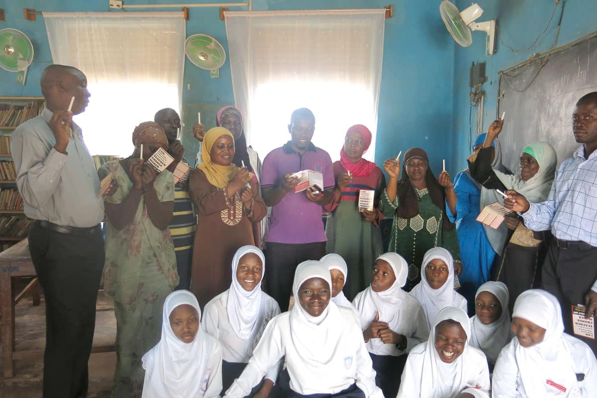 A group of African students and teachers hold chalk in a classroom