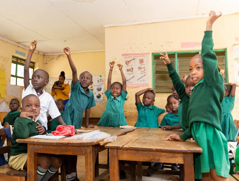 Primary school kids in Kenya raise their hands in a classroom
