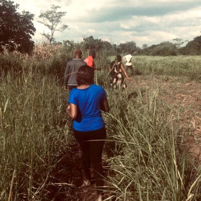 Program officers walk through a field in Uganda