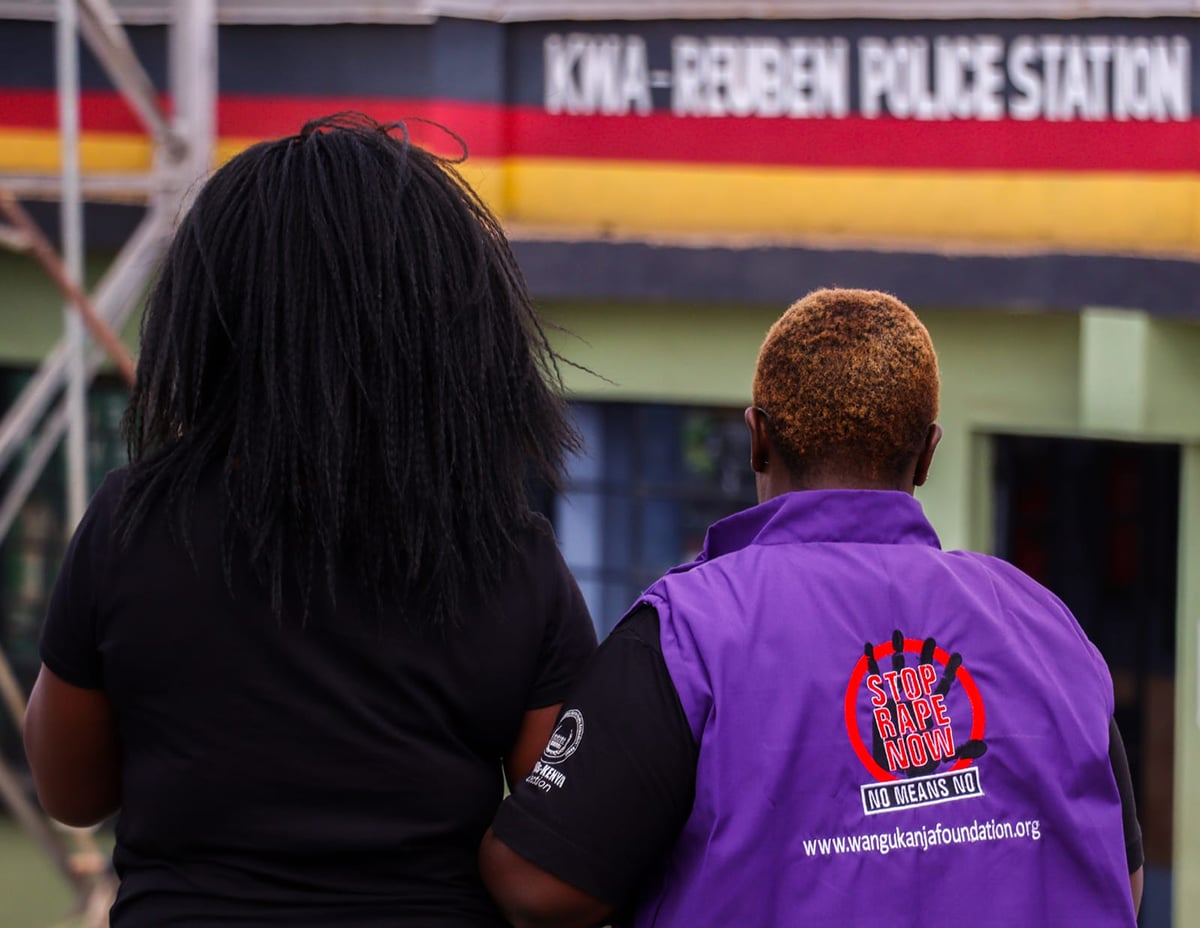 A person in a purple vest leads a female to a police station