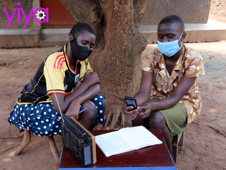 Two African schoolchildren in masks study with a radio and a mobile phone