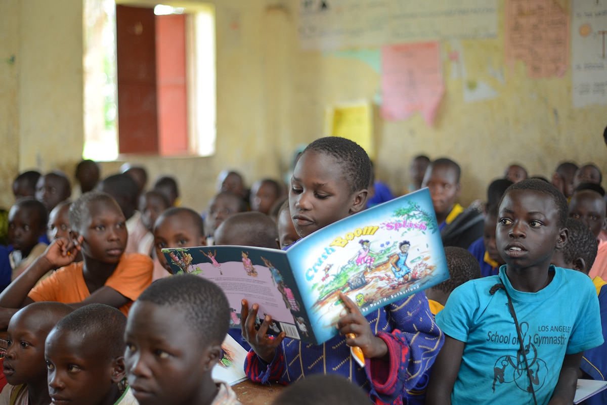 Dans une salle de classe bondée, un élève se lève pour lire un livre