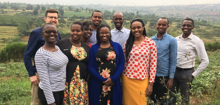 A group of smiling African adults stand on a hill in Rwanda