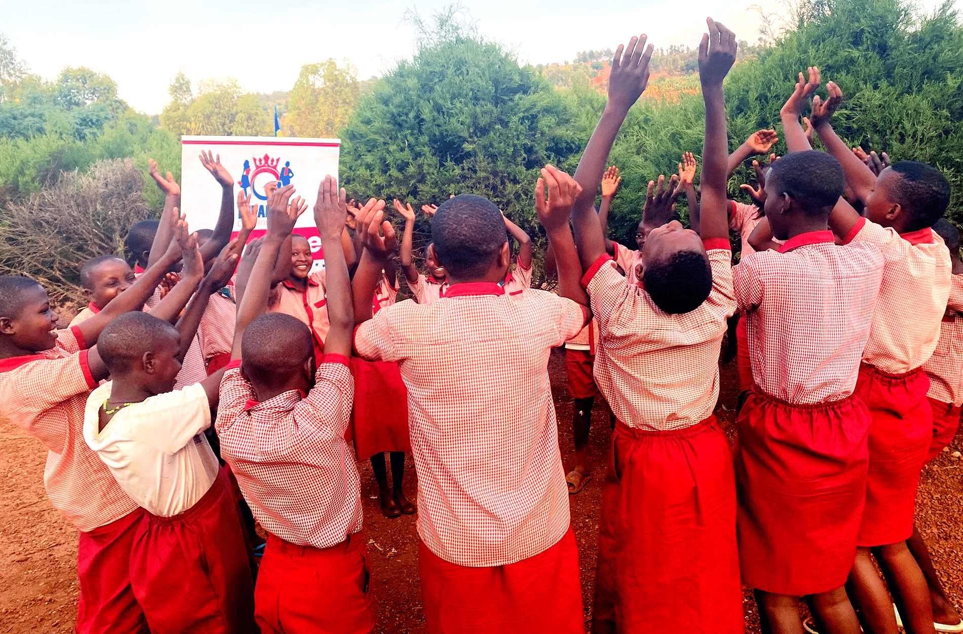 A circle of young girls in Rwanda raise their hands in joy
