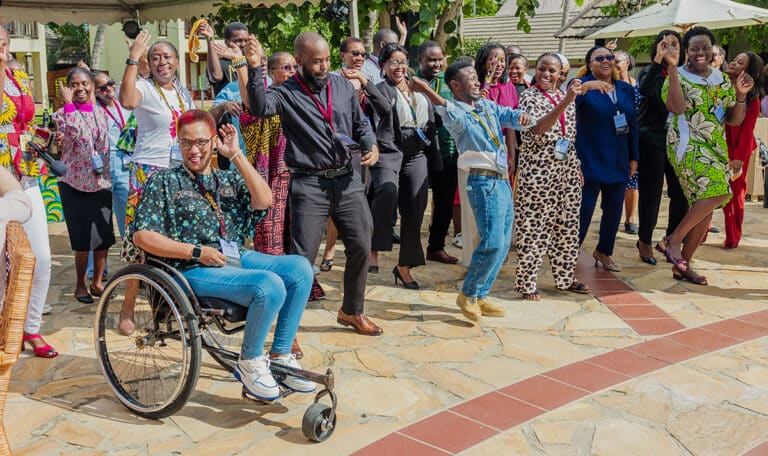 A group of Tanzanian adults sings and dances together outside