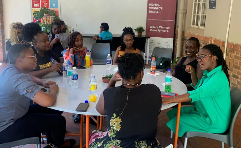 Un groupe de 7 femmes africaines assises autour d'une table en train de discuter